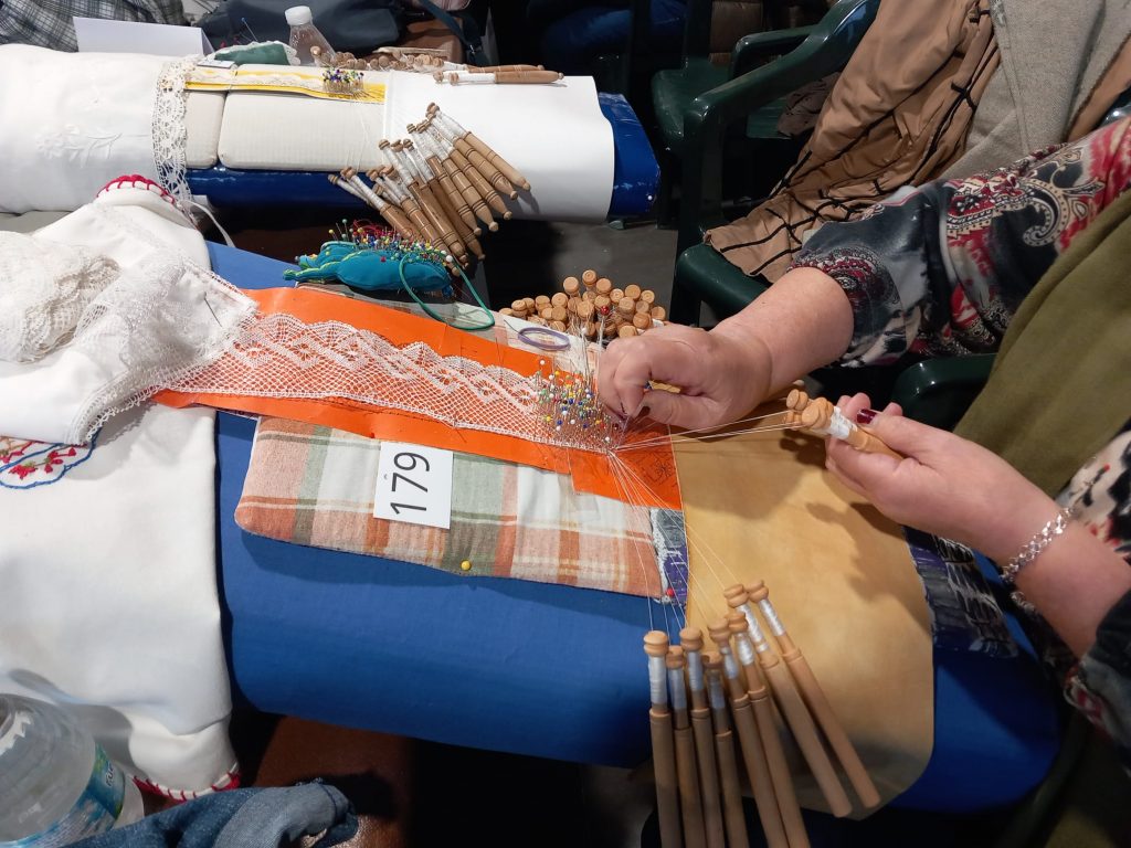 Una mujer hace encaje de bolillos